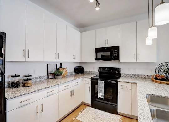 A kitchen with black appliances and white cabinets.