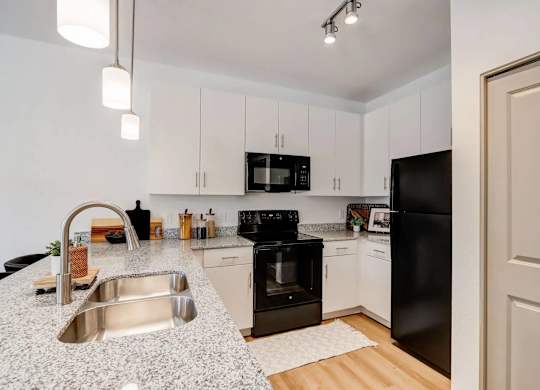 A kitchen with black appliances and white cabinets.