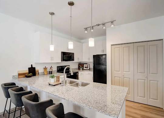 A kitchen with a granite countertop and a black refrigerator.