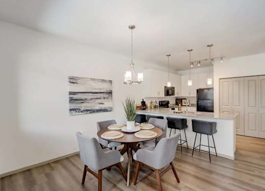 A dining room with a table set for two and a kitchen area in the background.