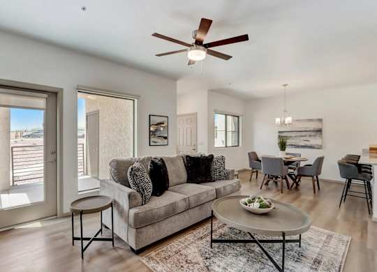 A living room with a grey couch and a ceiling fan.