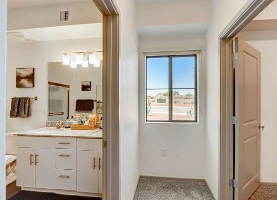 A bathroom with a large mirror and a window overlooking a parking lot.