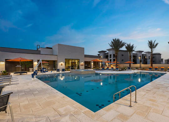 A large swimming pool surrounded by a tiled patio and lounge chairs.