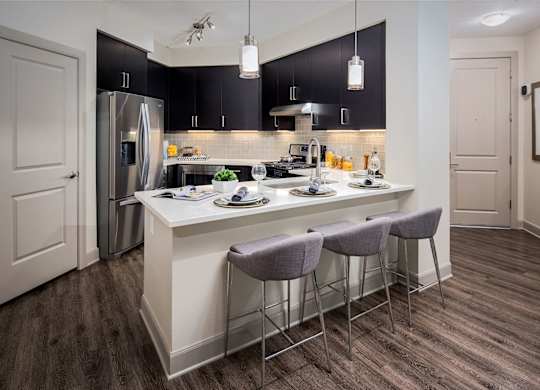 A kitchen with a white island and grey bar stools.