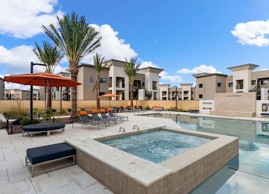 A pool area with a hot tub and lounge chairs.