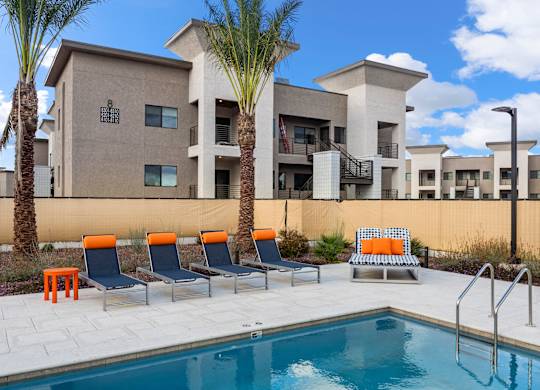 A pool area with chairs and a building in the background.