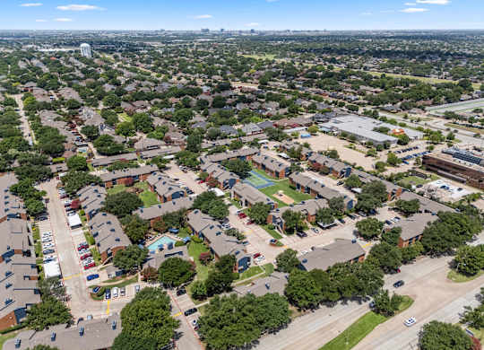 A bird's eye view of a residential area with houses, cars, and trees.