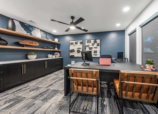A room with a desk, chairs, and a ceiling fan.
