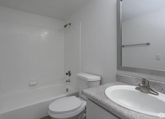 A white bathroom with a toilet, sink, and bathtub.