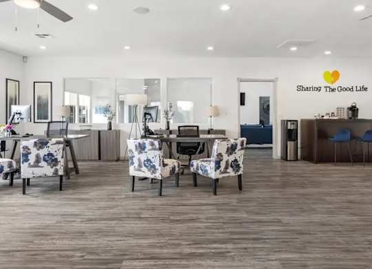 A room with a dining table set up with chairs and a logo on the wall that says "Sharing The Good Life".