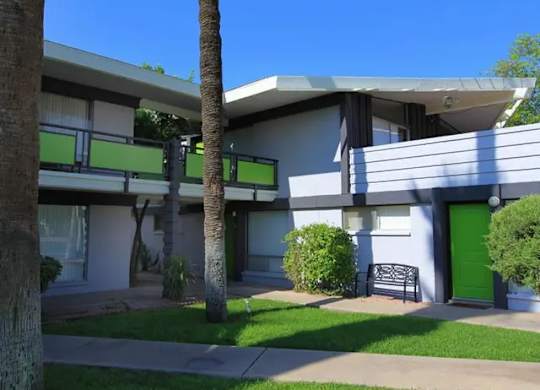 A building with a green door and a bench in front of it.