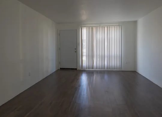 A room with wooden floors and a door with blinds on the window.