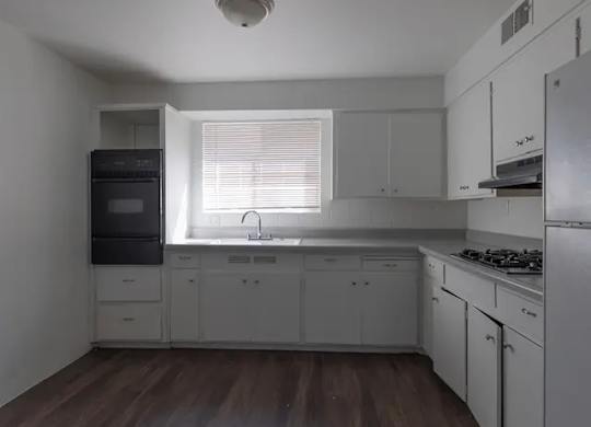 A kitchen with white cabinets and a black fridge.