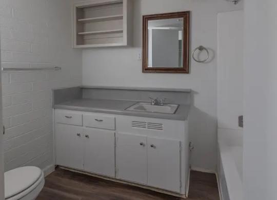 A white bathroom with a toilet, sink, and mirror.