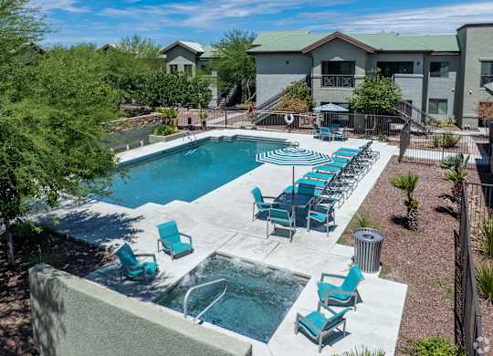 A pool with blue chairs and a hot tub in front of a building.