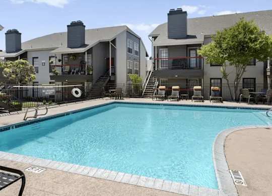 A swimming pool in front of a building with a black fence around it.
