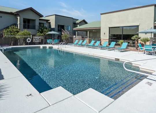 A swimming pool with blue water and lounge chairs.