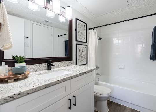 A bathroom with a white tub, sink, and toilet.