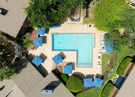 An aerial view of a pool surrounded by trees and umbrellas.