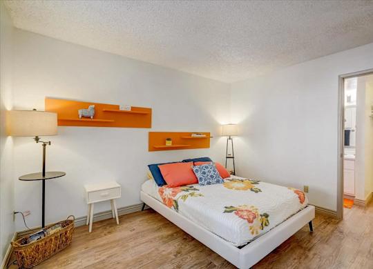 A bedroom with a bed, nightstands, and a lamp.