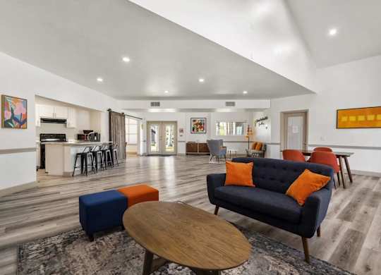 A living room with a blue couch and orange pillows.