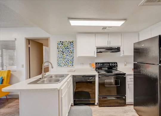 A kitchen with a black fridge and a white counter.