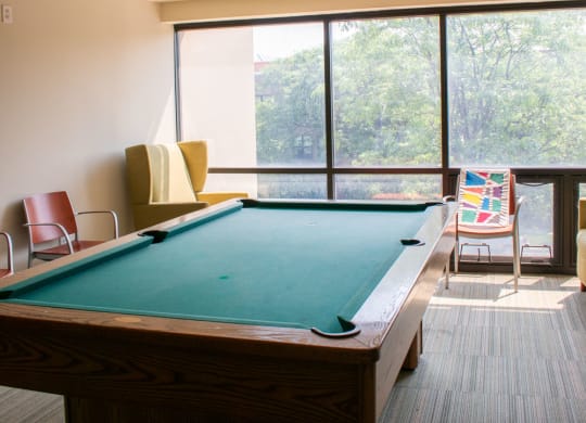 a pool table sits in the middle of a room with a large window