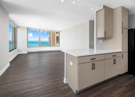 A kitchen with a black refrigerator and wooden floors.
