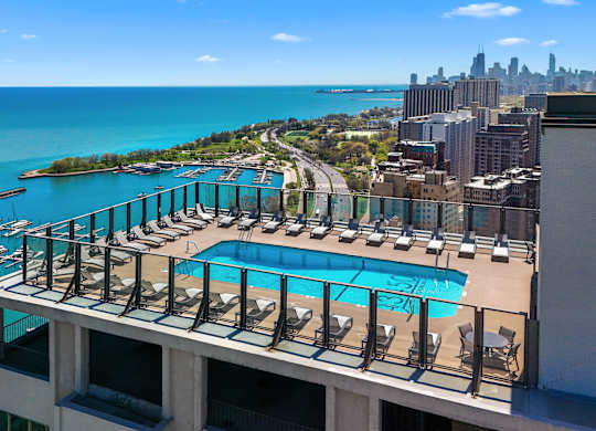 A marina with boats and a pool with chairs.