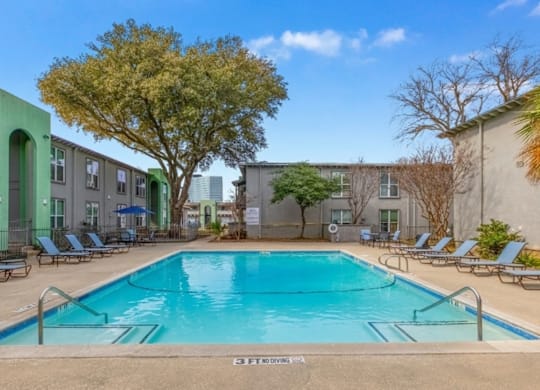 A swimming pool surrounded by lounge chairs and trees.