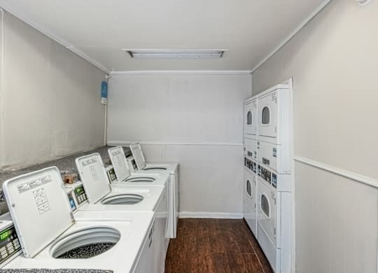 A row of white front load washing machines in a laundry room.