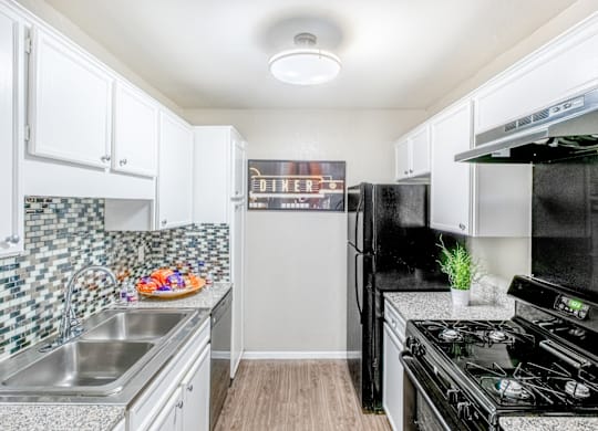 A kitchen with black appliances and white cabinets.