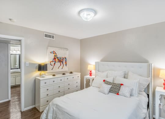 A bedroom with a large bed, a dresser, and a painting on the wall.
