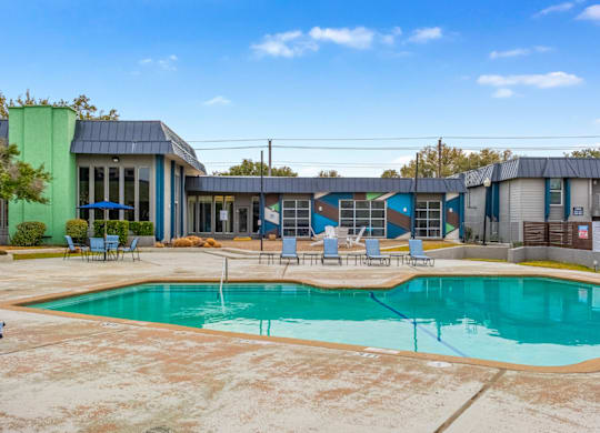 A swimming pool in front of a building with blue and green walls.