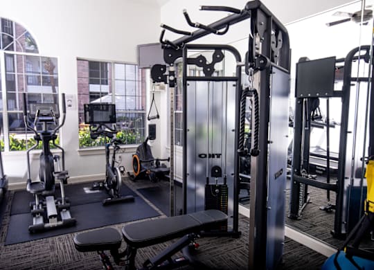 Gym with a variety of equipment including a treadmill, stationary bike, and weight machines at Whitney at the Heights, Texas