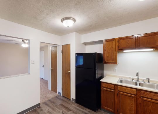 Wooden cabinets and black appliances with ceiling light at Quail Meadow Apartments, Cincinnati, Ohio