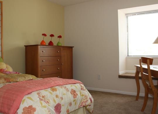 a bedroom with a bed and a dresser and a window  at Hunter's Creek Apartments, Ohio