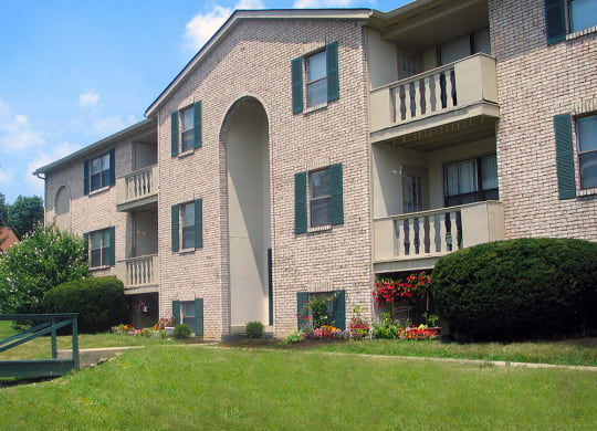 a large brick apartment building with a green lawn and bushes  at Four Worlds Apartments, Cincinnati