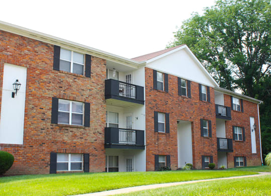 a brick and white building with a grass yard  at Four Worlds Apartments, Cincinnati