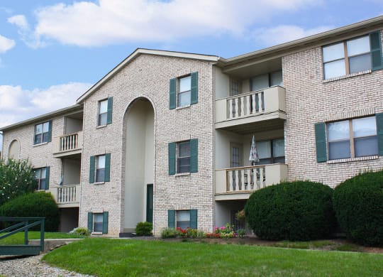 an exterior view of a brick apartment building with green grass and shrubs  at Four Worlds Apartments, Ohio, 45231