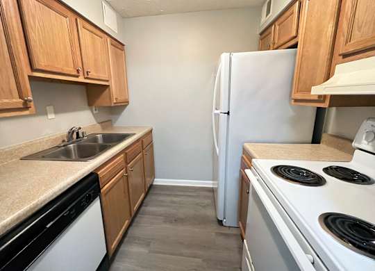 A kitchen with a white fridge, black stove, and wooden cabinets.