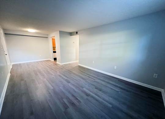 A room with wooden flooring and white walls.