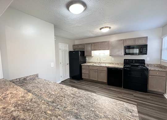 an empty kitchen with black appliances and a granite counter top at Revere Village Apartments, Centerville, 45458