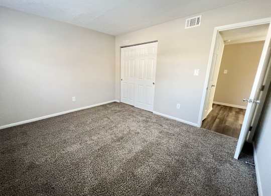 an empty living room with carpet and a door to a bedroom at Revere Village Apartments, Centerville, OH, 45458