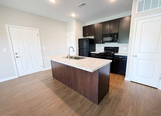 A kitchen with a white countertop and dark brown cabinets.