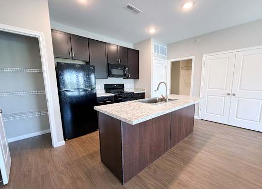 A kitchen with a black refrigerator, microwave, and stove.
