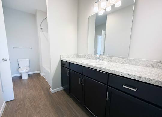 A bathroom with a toilet, sink, and mirror.