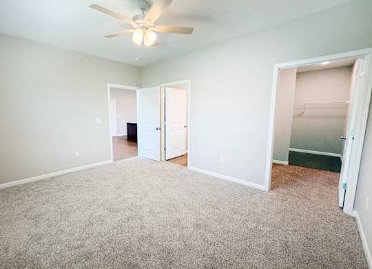 A room with a ceiling fan and carpeted floor.