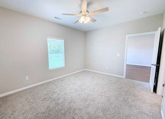 A room with a ceiling fan and carpeted floor.