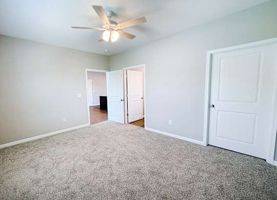 A room with a ceiling fan and carpeted floor.